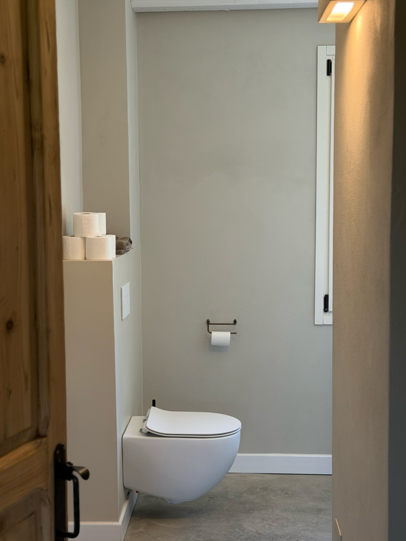 Minimal en-suite bathroom with soft plaster walls and warm light